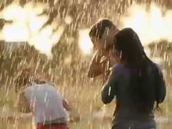 Three girls playing in front of a lawn sprinkler in a park Stock Footage