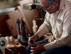 MS TD TU boot maker using tool to stretch leather and place tacks in sole of cowboy boot Stock Footage