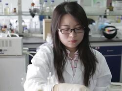 Asian female scientist looking at beaker of liquid Stock Footage