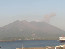 Ash erupts from Sakurajima volcano as it bears over Kagoshim port, Japan Stock Footage