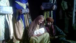 Virgin Mary sitting on floor of manger holding baby Jesus with Joseph and three wise men standing nearby Stock Footage