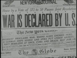President Woodrow Wilson signs a declaration of war against Germany; a newspaper headline reads, War Is Declared By U.S.; soldiers work digging and raking in a military camp lined with tents. News Clip