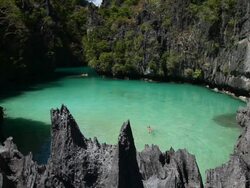 WS of caucasian woman swimming in idyllic tropical inlet surrounded limestone cliffs / Small Lagoon, Miniloc Island, Bacuit Archipelago, El Nido, Palawan, Philippines Stock Footage