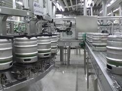 MS Shot of Aluminum beer barrels moving on conveyor at beer production at brewery, Bitburger Pils Stock Footage