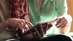 Young couple on motel bed scan and scroll across tablet screen Stock Footage