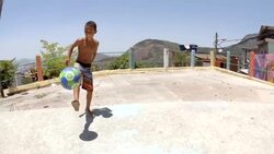 Young Brazilian boy juggles soccer ball in slow motion over Rio slum Stock Footage