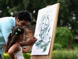 Man teaching painting to his daughter on a easel  Stock Footage