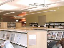 WS PAN public library reading room for newspapers magazines and music CDs with patrons browsing shelves for casual reading / Rancho Mirage, California, USA Stock Footage