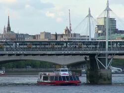 MS Train passing on and boat passing under Hungerford Bridge in Thames River / London, United Kingdom Stock Footage