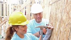 Foreman helps young female volunteer as they build home for charity Stock Footage