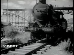 1944: CHINESE TRANSPORTATION: RAILROAD: LA Locomotive moving slow down track, bridge construction above BG. HA WS Workers, some in turbans, building railroad tracks. Three men working in unison, teamwork, w/ lever poles trying to move tracks from ties Instructional Video