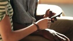 Excited couple sit and scroll through smartphone on motel bed Stock Footage