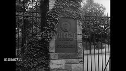 1939: BRIGGS HEADS COMMITTEE: EXT National Bureau of Standards gate. Director Dr. Lyman J. Briggs (1874-1963) making notes on blackboard (Uranium Committee aka Advisory Committee) CU Dr. Tuve sitting talking. Instructional Video