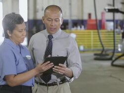 MS Mechanic and manager holding tablet computer for discuss something while standing in auto shop / Seattle, Washington, United States  Stock Footage