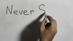 Hand writing a 'Never Stop Dreaming' message on a white board using a black marker Stock Footage