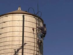 A tower climber descends the ladder of a water tower in New York City. Stock Footage
