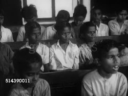 1949: INDIA CASTE SYSTEM: OUTCASTS / UNTOUCHABLES: Hut home w/ mother & son exiting home, mother combing boy's hair, boy walking to school through town. VS Public school room w/ children sitting at bench desks. VS Children & teacher in classroom. Instructional Video