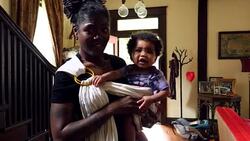 MS Smiling mother playing with infant daughter in sling carrier in living room Stock Footage
