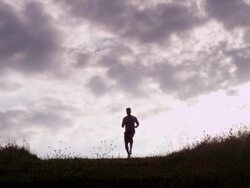 WS handheld silhouette male athlete running down hill  Stock Footage