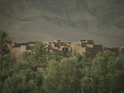 A fort like building stands in the Moroccan landscape, surrounded by trees and hills. Stock Footage