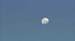 A waning gibbous moon shines in a blue sky. Stock Footage