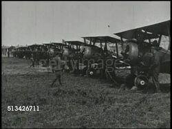 1910s: WORLD WAR I FIGHTER AIRPLANES: VS United States soldiers wheeling out biplane fighter aircraft from hangar, row of biplanes on field, ace pilot Edward Rickenbacker (1890-1973) sitting in plane, soldiers loading bombs, plane on field. WWI Instructional Video