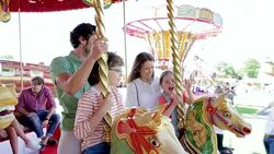 Family riding carousel in amusement park Stock Footage
