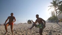 Soccer ball falls through air to Brazilian team in beach footvolley match Stock Footage