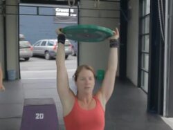Camera tracks around Jean Anne as she performs series of overhead lunges. Stock Footage