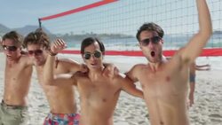 Playful young men cheering at beach volleyball net Stock Footage