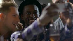 Friends gather around smartphone to take group selfie in crowded bar Stock Footage