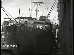 1946: FRANCE EXPORTS: MS Stern side of ship in dock. WS Crane w/ crates, boxes lifting to dock. (possibly wine crates). MS American worker. WS Workers pulling in crane full of crates. CU Crate 'Porcelain, New York imported from France' Ship yard Instructional Video