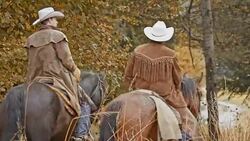 Two cowboys riding their horses on country road Stock Footage
