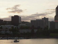 WS View of Boats pass in front of marina next to city of Portland with sun sets  / Portland, Oregon, United States  Stock Footage