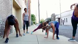 MS Group of women stretching together on sidewalk of city street before morning run Stock Footage