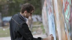 Young man sprays paint on graffiti wall Stock Footage