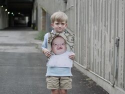 Slow motion push of young boy holding up baby photo of himself with cleft palate. Stock Footage