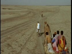 WA High angle, Man on bike and family on cart moving through desert, Gujarat, India Stock Footage