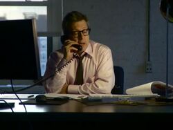 Medium shot. Dolly to the left around man at his desk working late and talking on the phone. Stock Footage