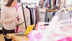 Clothing shop owner checking inventory with scanner Stock Footage