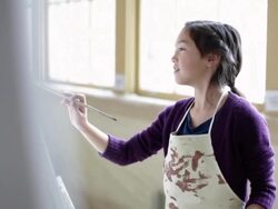 Girl painting on easel in art class Stock Footage