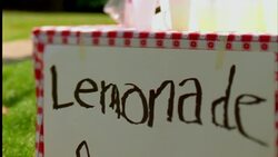 A young boy at a lemonade stand holds out a glass of lemonade. Stock Footage