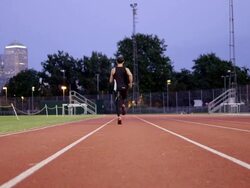 MS to WS male athlete running on track away from camera Stock Footage