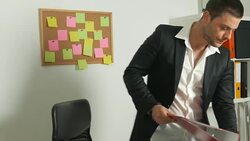 Young man working in the office stands up to take a folder and then reads from it Stock Footage