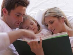 Family In Bed Reading Book Together Stock Footage