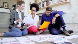 Creative business people reviewing and discussing proofs on office floor Stock Footage