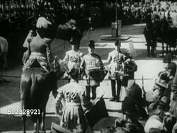 1953: LONDON, ENGLAND: ANNOUNCEMENT CEREMONY: VS Buckingham Palace, HA WS Royal Herald standing in street w/ others formally proclaiming date for Coronation of Elizabeth II (SOT Garbled, except 'God save the Queen'), WS Noblemen, clergy & trumpeters. Instructional Video