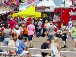 Concession stands at a hot, crowded State Fair; people walk by camera. Stock Footage
