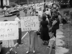 B/W 1950s pro-segregation protestors with children standing with mispelled signs outside of school Stock Footage