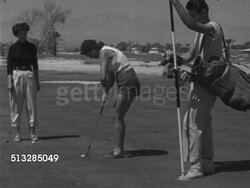 1952: LAS VEGAS, NEVADA: GOLFING: WS Female golfer in shorts putting  ball toward hole on 16th green, female & male caddie standing, watching.   Upscale, upper class, luxury, leisure, sport, relaxing. Instructional Video